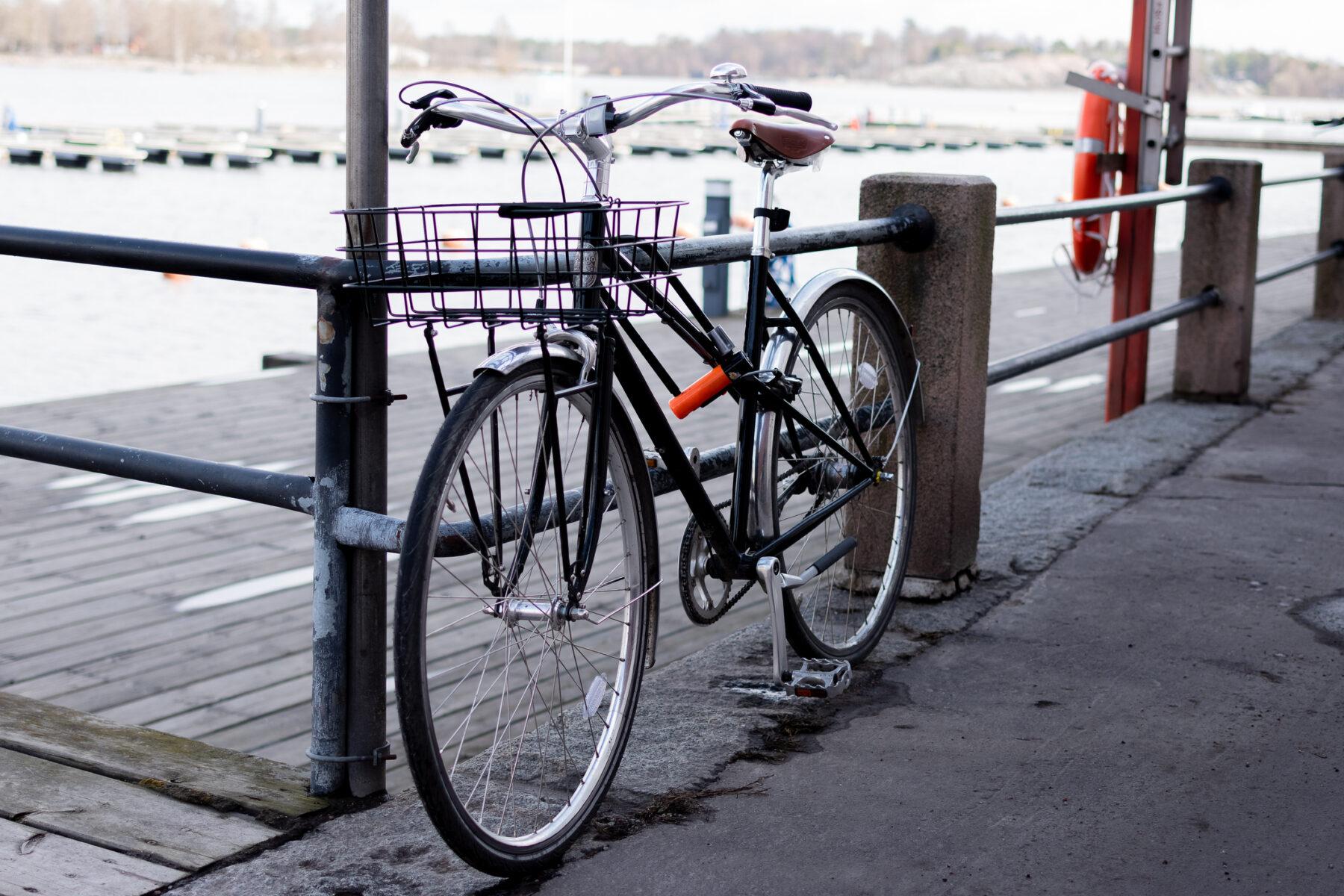 bicycle with a basket on the front is parked on a sidewalk